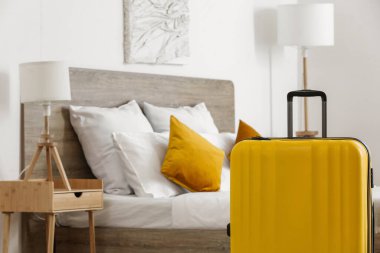 Hafif otel odasında, yatağın yanında bavul, yakın plan.