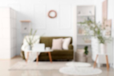 Yeşil kanepeli şık bir oda, kahve masası ve çiçek açan dallar, bulanık bir manzara.