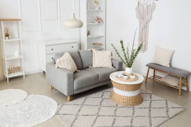 Konforlu kanepe, kahve masası ve güzel oturma odasında çiçek açan dalları olan vazo.