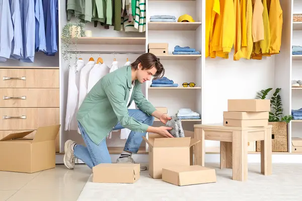 Handsome young man unpacking wardrobe boxes with stylish clothes in dressing room