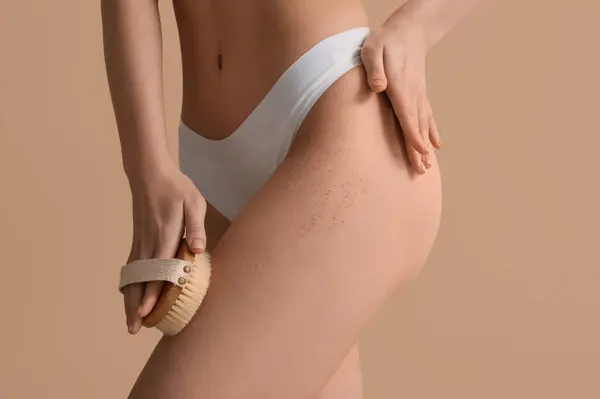 Young Woman Massage Brush Scrubbing Leg Beige Background Imagen de stock