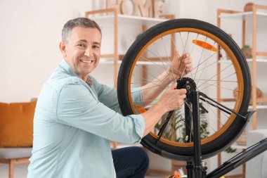 Evde bisiklet tekerleğini tamir eden olgun bir adam.