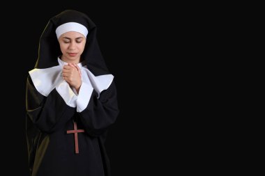 Siyah arka planda dua eden genç bir rahibe