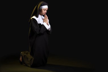 Siyah arka planda dua eden genç bir rahibe