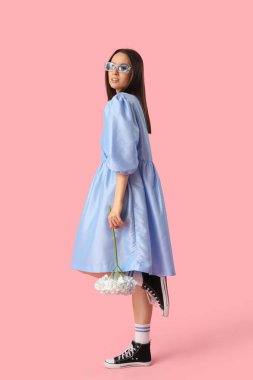 Pembe arka planda ortanca çiçekleri olan güzel, genç, moda bir kadın.