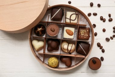 Lezzetli şekerlerle dolu bir kutu ve ahşap arka planda kahve çekirdekleri.