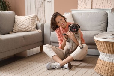 Oturma odasında yerde oturan sevimli köpekli genç bir kadın.