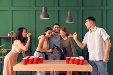 Bir grup genç arkadaş partide bira pong oynuyorlar.