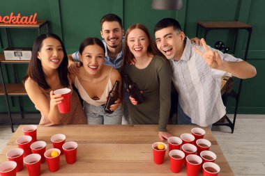 Bir grup genç arkadaş partide bira pong oynuyorlar.