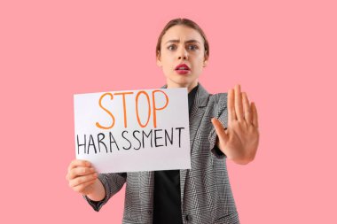Elinde pembe arka planda DUR HARASSMENT yazan kağıt tutan genç iş kadını