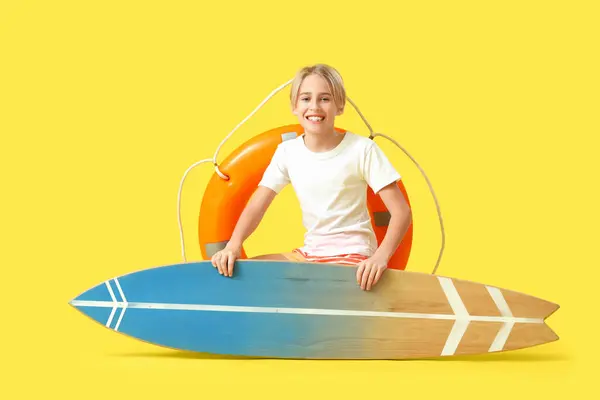 stock image Happy little boy lifeguard with ring buoy and surfboard on yellow background