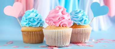 Lezzetli kekler ve açık mavi arka planda kağıt kalpler. Cinsiyet gösterme partisi afişi 