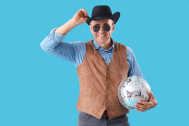 Mavi arka planda disko topu olan olgun bir kovboy.