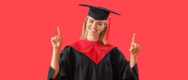 Kız öğrenci kırmızı arka planda bir şeye işaret ediyor.