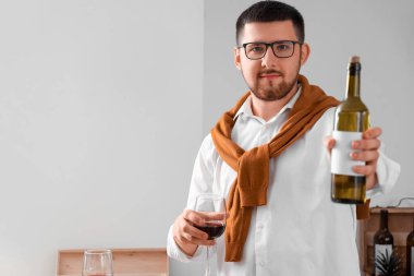 Genç şarap garsonu elinde şişe ve bir bardak şarapla evde.