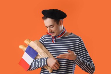 Fransız bayrağı ve turuncu arka planda ekmekleri olan yakışıklı adam.