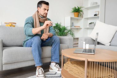 Hasta genç adam termometreyi evdeki doktora gösteriyor.