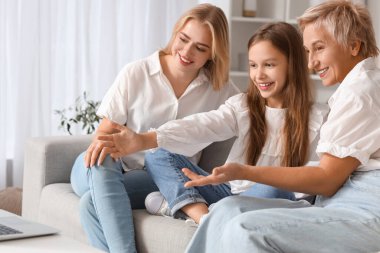 Annesi ve büyükannesiyle evde sohbet eden küçük bir kız.