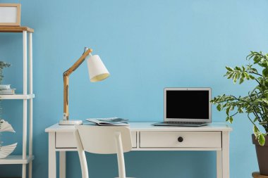 Modern dizüstü bilgisayarı ve renkli duvarın yanında dergileri olan rahat bir iş yeri.