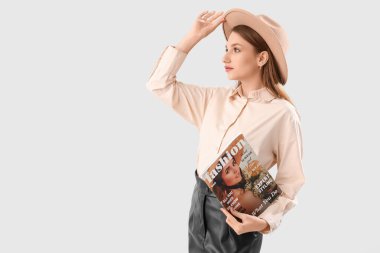 Beyaz arka planda moda dergisiyle genç bir kadın.