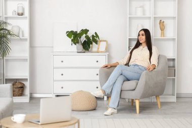 Evdeki koltukta oturan güzel kadın.