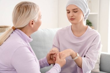 Kemoterapiden sonra genç bir kadın. Annesi evde el ele tutuşurken. Mide kanseri kavramı