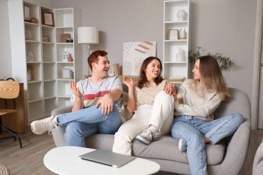 Genç arkadaşlar oturma odasında kanepede sohbet ediyorlar.