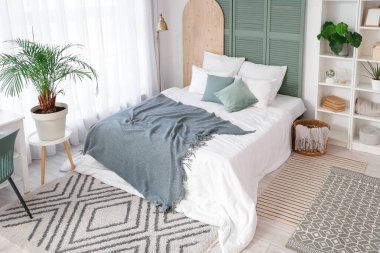 Yatak odasının içinde raf ünitesi, bitki ve lamba var.