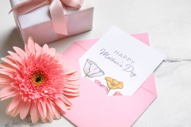 Zarfta neşeli kartpostal, hediye kutusu ve beyaz grunge arka planda çiçek var. Anneler Günün kutlu olsun.