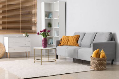 Masanın üzerinde güzel mor laleler olan modern oturma odası ve vazo.