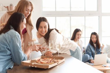 Şampanyalı ve pizzalı genç kadınlar mutfakta cep telefonu kullanıyorlar.