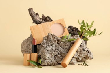 Taşlı makyaj ürünleri, ağaç kabuğu ve açık sarı arkaplanda yeşil dallar. Eko biçimi kavramı