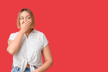 Kırmızı arka planda şok olmuş yetişkin bir kadın.