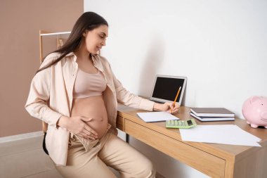 Evdeki not defterine yazan hamile bir kadın. Annelik Faydası kavramı