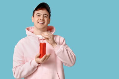 Mavi arka planda soda kutusu olan genç adam.