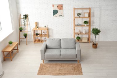 Beyaz tuğla duvarın yanında kanepesi olan modern oturma odası.