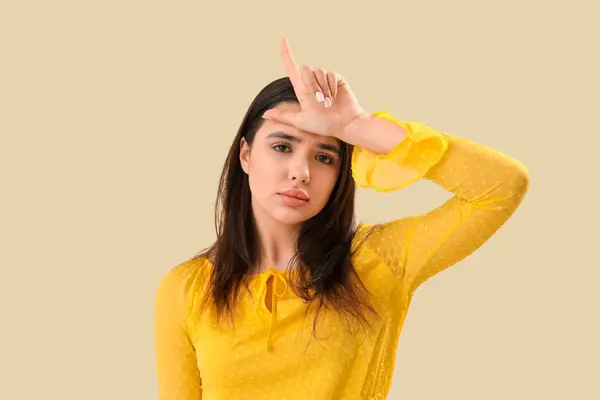 stock image Upset young woman showing loser gesture on beige background, closeup