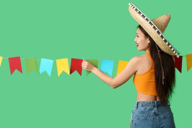 Meksika şapkalı ve yeşil arka planda çelengi olan mutlu genç kadın.