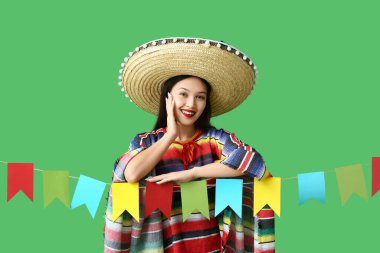 Meksika elbiseli ve yeşil arka planda çelengi olan mutlu genç bir kadın.