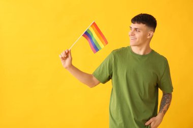 Sarı arka planda LGBT bayrağı olan yakışıklı genç adam.