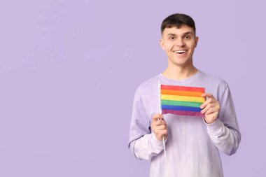 Mor arka planda LGBT bayrağı olan yakışıklı genç adam.