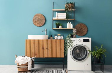 Çamaşır makinesi, lavabo ve sepeti olan bir çamaşırhane.