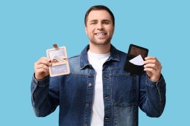 Cüzdanı mavi arka planda olan genç bir adam.