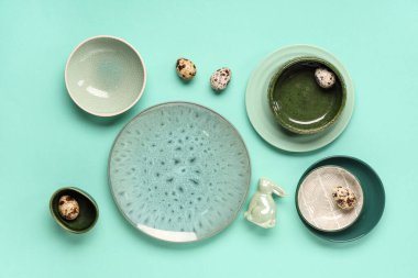 Paskalya yumurtaları ve turkuaz arka planda oyuncak tavşanlarla süslü bir masa.