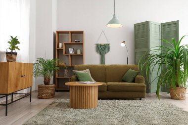 Yeşil kanepesi, masası ve raf ünitesi olan şık bir oturma odası.