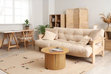 Oturma odasının içinde bej kanepe ve masalar var.