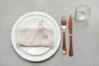 Gri arkaplanda altın çatal bıçak seti olan güzel bir masa.