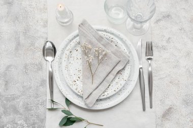 Gri arkaplanda yapraklar ve çigila çiçekleri olan güzel bir masa.