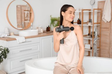 Banyoda vurmalı masaj aleti olan genç bir kadın.