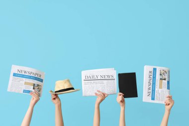 Renkli arka planda gazete, şapka ve defter bulunan kadın elleri
